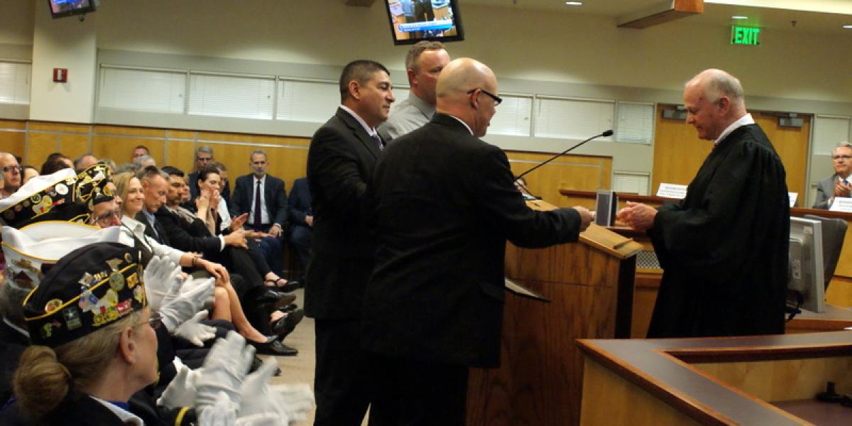 Judge John Colborn (right) presents commemorative coins to newly-sworn Veterans Treatment Court mentors during April opening ceremonies