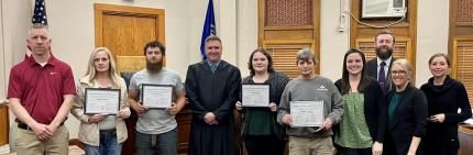 Photo (Front Row): Officer Marty Metschke, Graduate Asley, Graduate Brody, Judge Richard Smith, Graduate Leah, Graduate Brian, Officer Chelsea Hagedorn, and Assistant Probation Officer Chelsea Byfield.  (Back Row): Drug Court Prosecutor Seth Hawkins and Drug Court Defense Attorney Linday Mahoney.