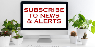 Subscribe to news and alerts - text on a computer screen on a desk with plants